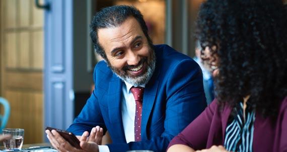 Un homme et une femme assis à une table regardent un téléphone mobile.