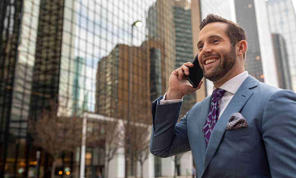 Business man talks on cell phone on city sidewalk