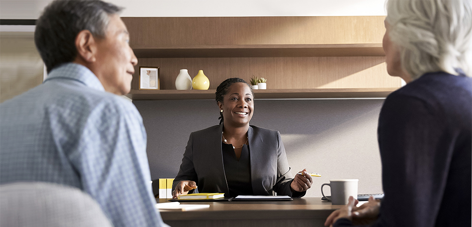 Business women at desk conversing with a man and woman