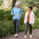 Two women walking briskly in park, conversing